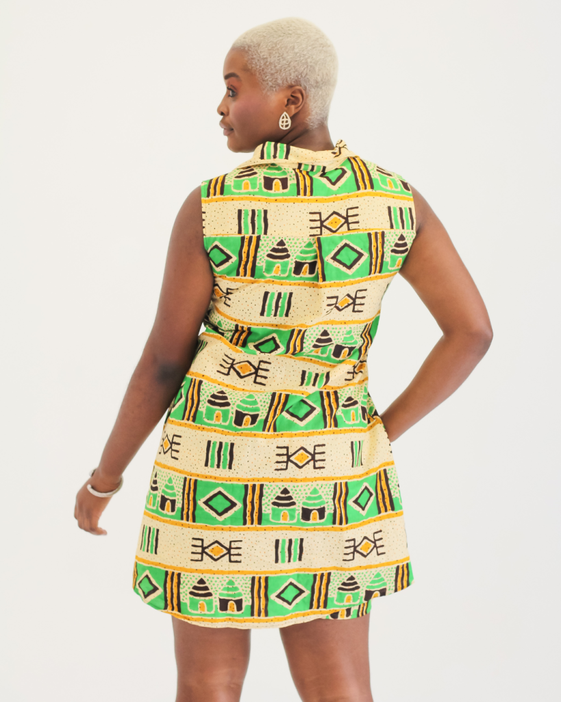 Mulher negra, vestindo um vestido amarelo e verde com símbolos étnicos .